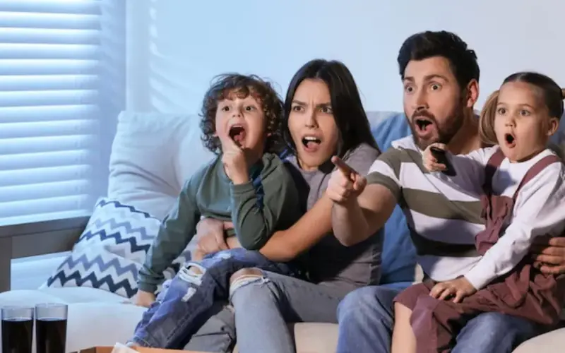 Família e amigos reunidos diante da TV na sala