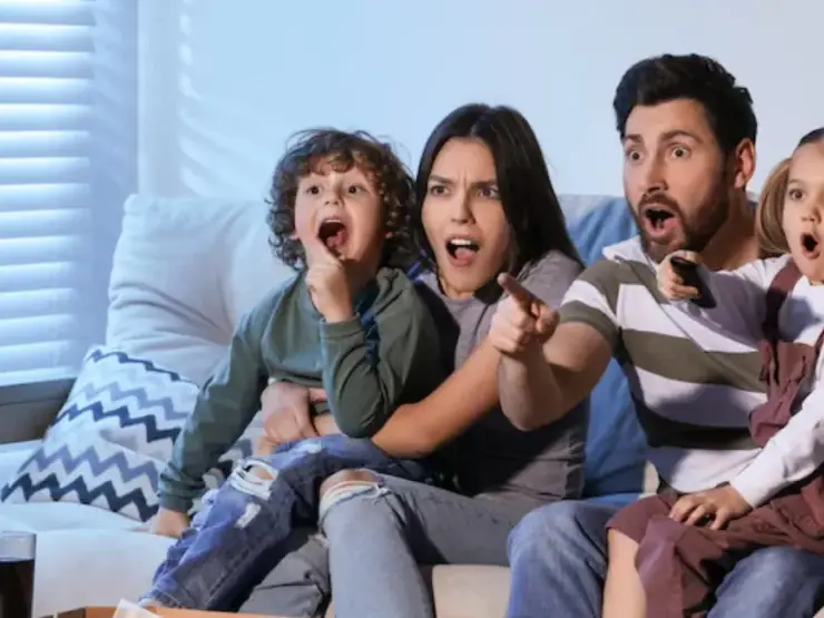 Família e amigos reunidos diante da TV na sala