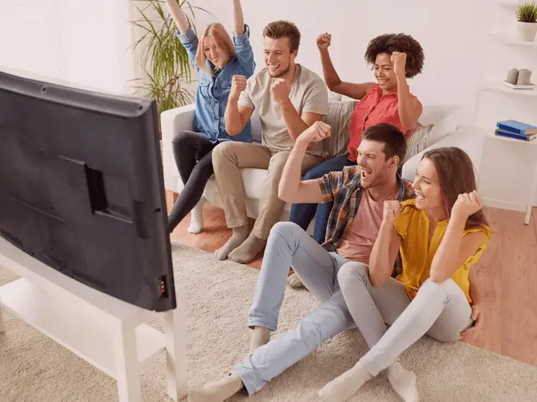 Família e amigos reunidos diante da TV na sala