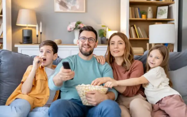 Família e amigos reunidos diante da TV na sala
