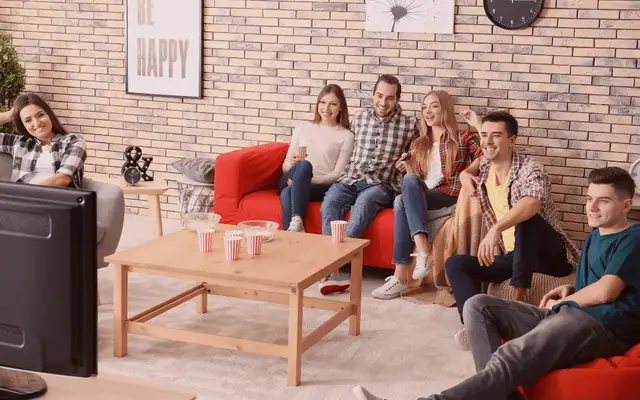 Família e amigos reunidos diante da TV na sala