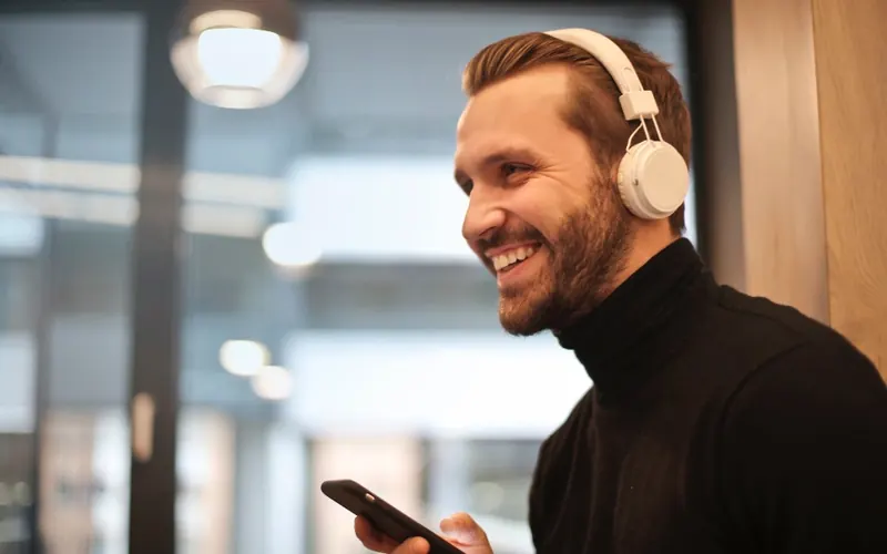 Homem com celular e fones de ouvido no escritório