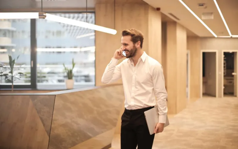 Homem com celular e notebook no escritório
