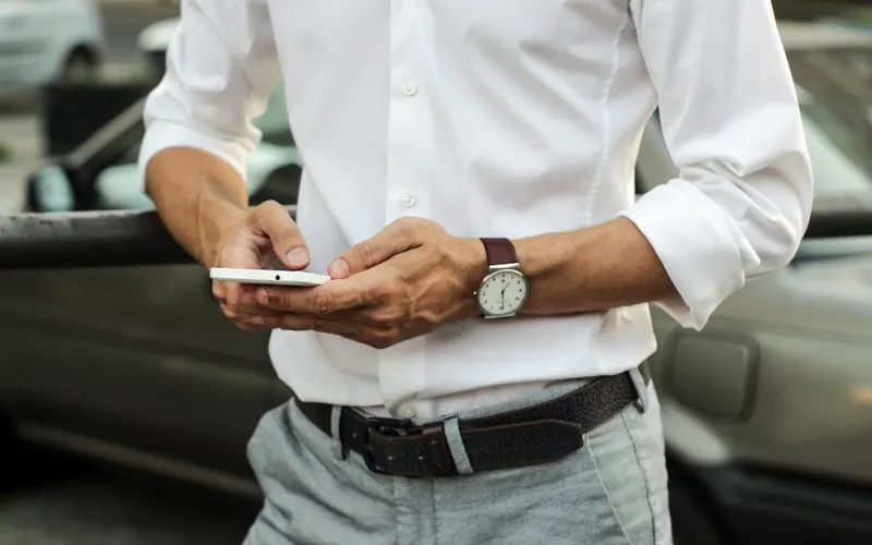 Homem com celular e relógio na cidade