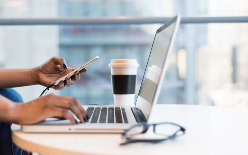 Mulher com celular e notebook no escritório